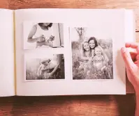 Otwarty album z czarno-białymi zdjęciami rodzinnymi leżący na drewnianym stole. Fotografie przedstawiają kobietę w ciąży i matkę z córkami, symbolizując codzienne życie, troski doczesne i przemijanie czasu.