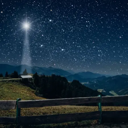 Gwiazda Betlejemska świecąca nad pastwiskiem i stajnią w górach. Wieczorna scena wigilijna.