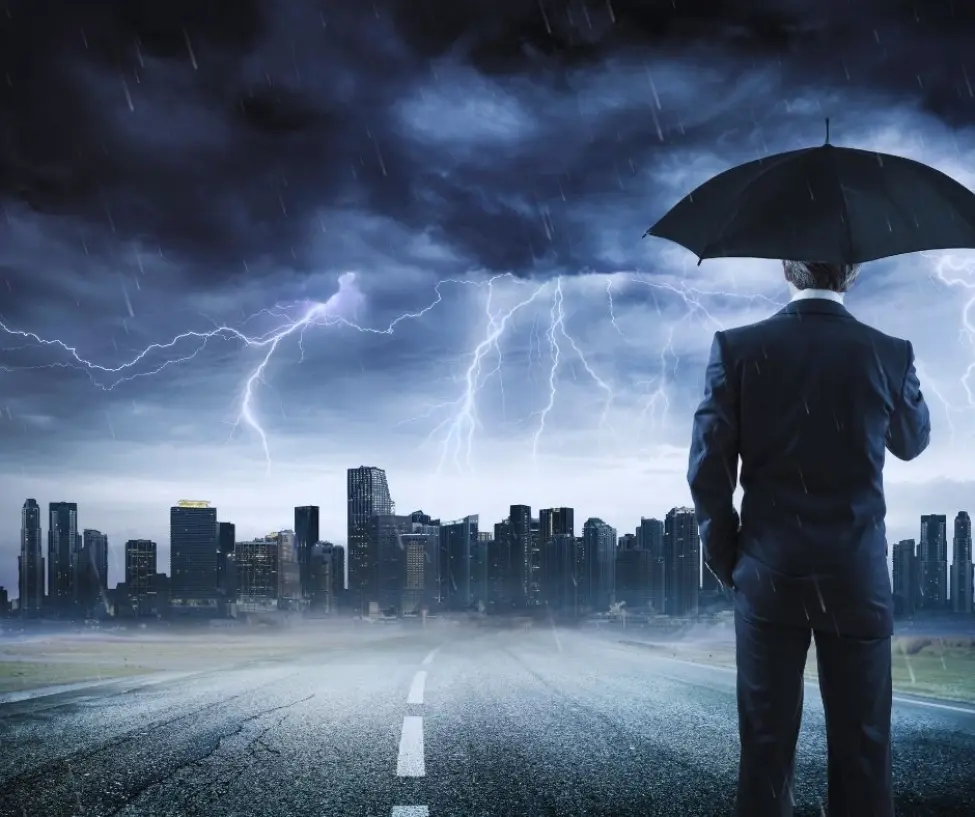 Mężczyzna w garniturze z parasolem stojący na drodze przed nowoczesnym miastem podczas gwałtownej burzy z piorunami. Obraz symbolizuje człowieka stawiającego czoła troskom doczesnym i nadchodzącym zmianom.